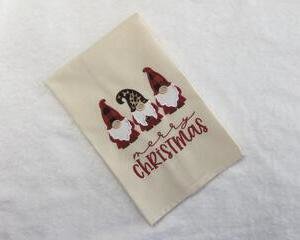 This teal towel is adorned with appliqued gnomes with Merry Christmas embroidered underneath the three gnomes