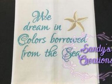 Tea Towel embroidered with a star fish with the saying, We dream in colors borrowed from the searoduct image